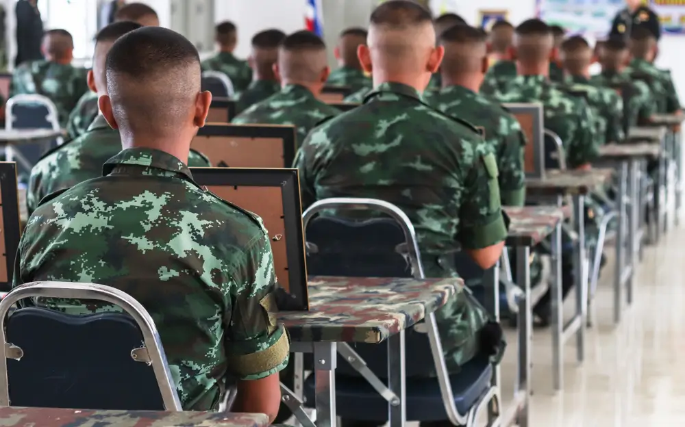 Alumnos en uniforme de formación sentados en pupitres dentro de un aula de la academia de policía.
