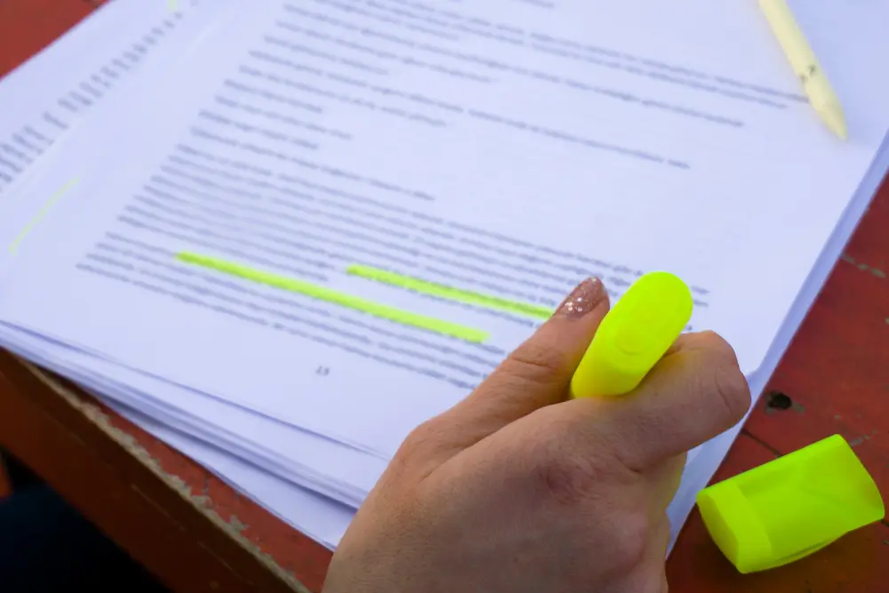Mujer subrayando leyes y apuntes con un marcador amarillo para estudiar el temario de ciencias jurídicas.
