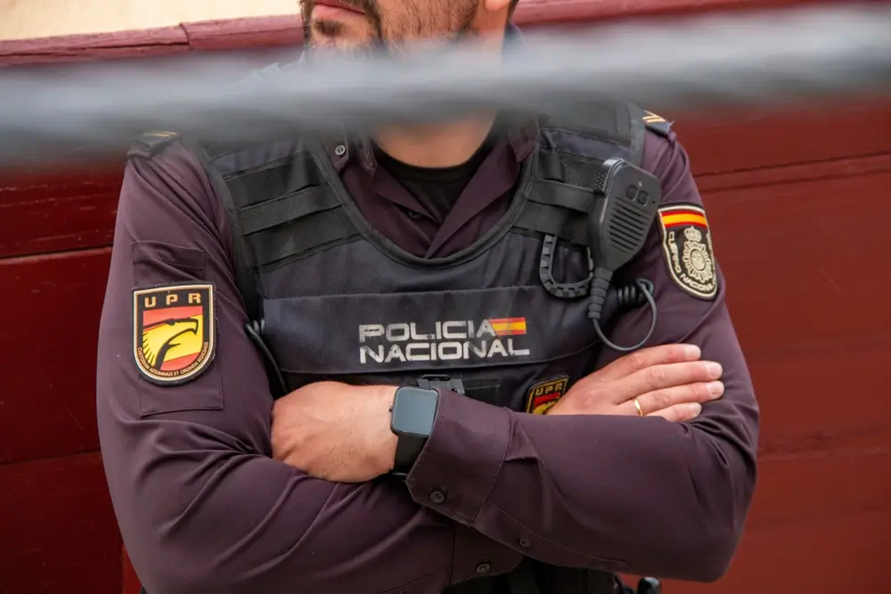 Agente de la Policía Nacional con uniforme de la UPR y brazos cruzados en un acto oficial de jura de cargo.