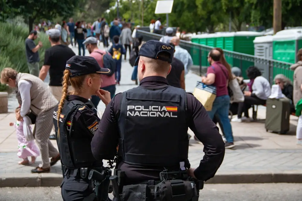 Agentes de la Policía Nacional con su equipo policial y placa de identificación patrullando una zona urbana concurrida.