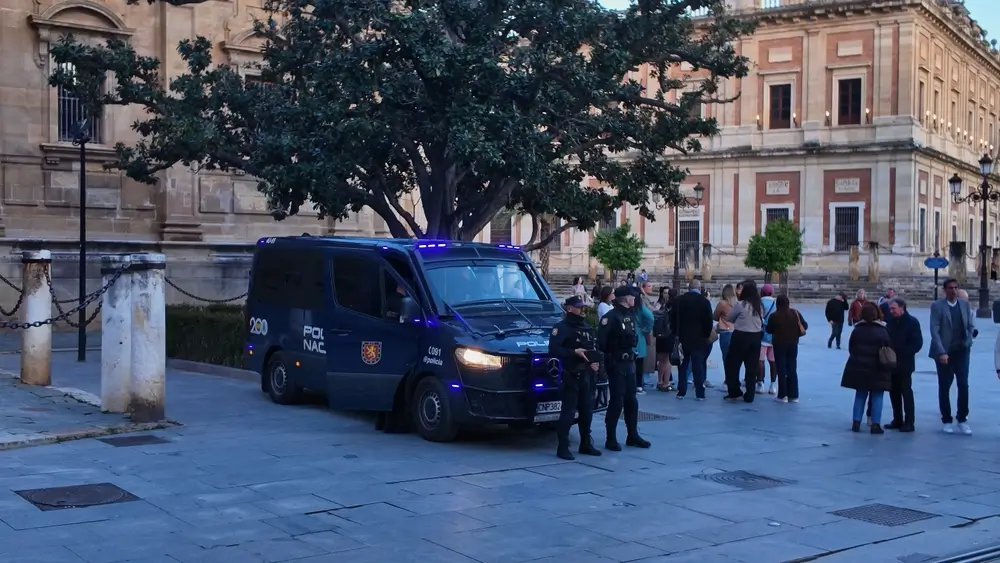 Agentes de la Policía Nacional uniformados junto a un furgón patrulla en una plaza, labor diaria de un agente de policía.