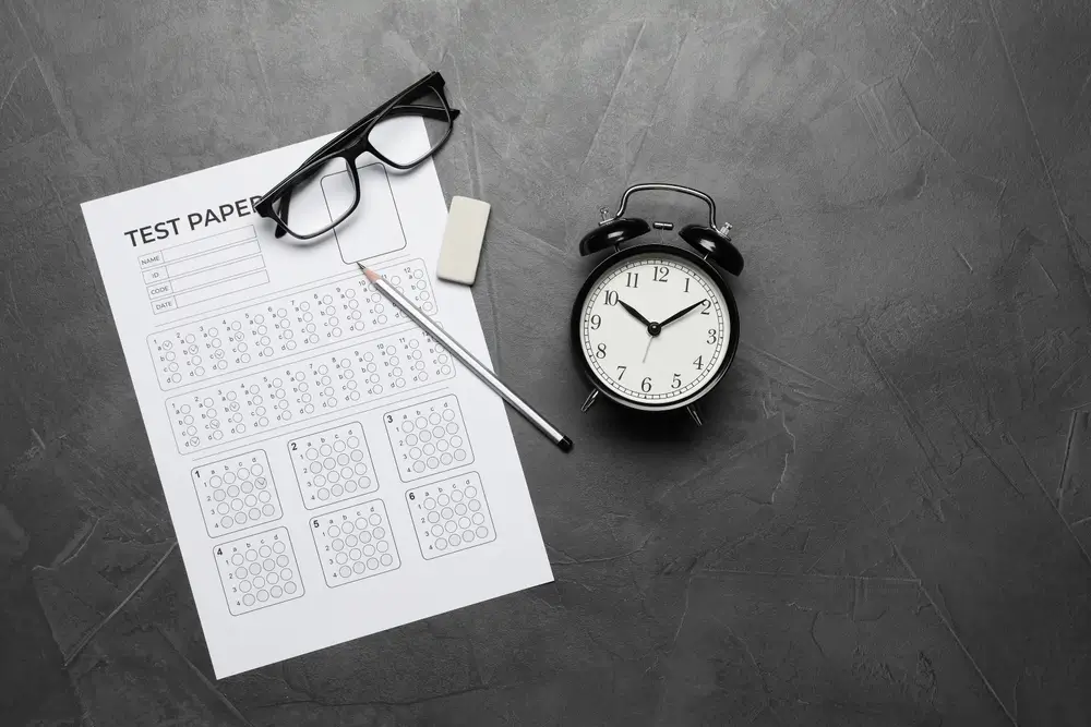 Examen psicotécnico de opositor a policía con reloj, lápiz y gafas sobre la mesa para calcular la nota del test.