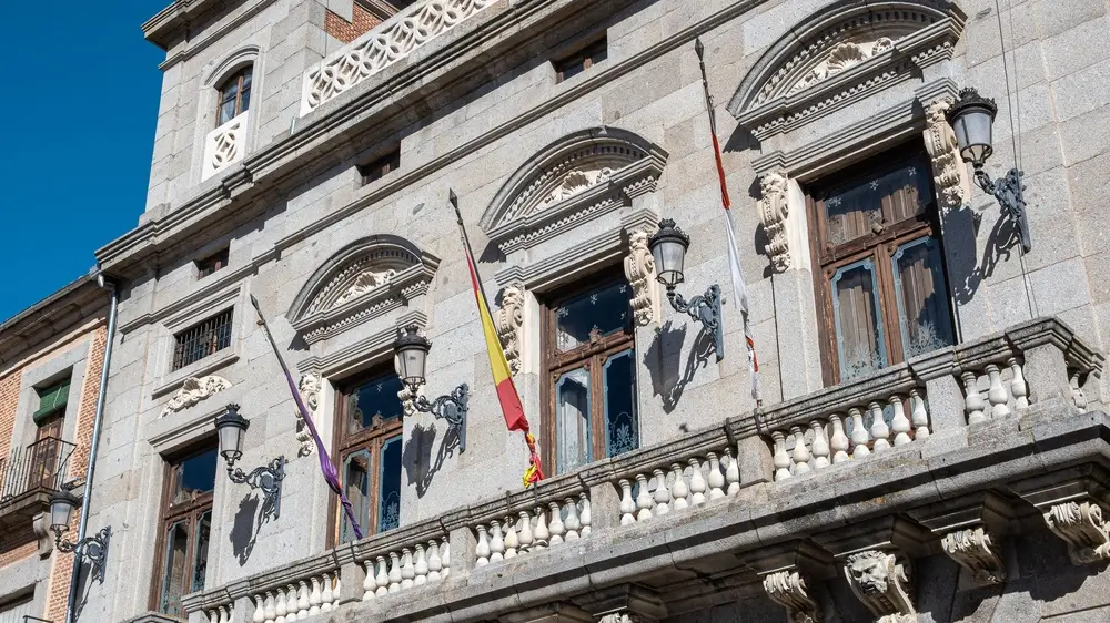 Fachada de piedra de la Escuela Nacional de Policía en Ávila con banderas en sus balcones clásicos.