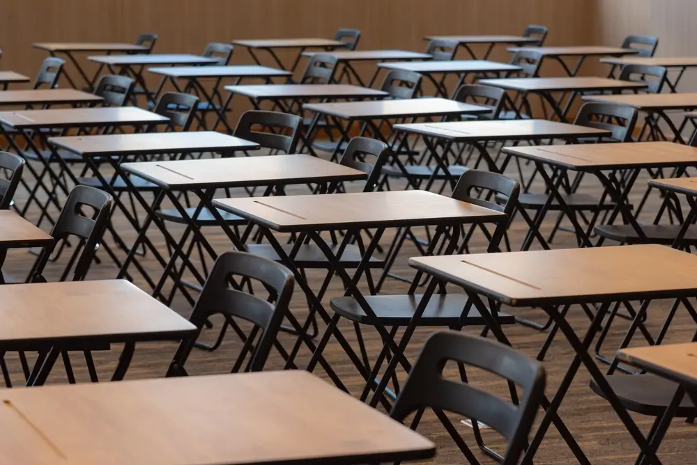 Filas de pupitres y sillas en un aula de examen vacía para oposiciones y pruebas psicotécnicas.