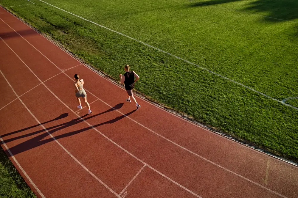 Dos opositores corriendo en una pista de atletismo durante la realización de pruebas físicas.