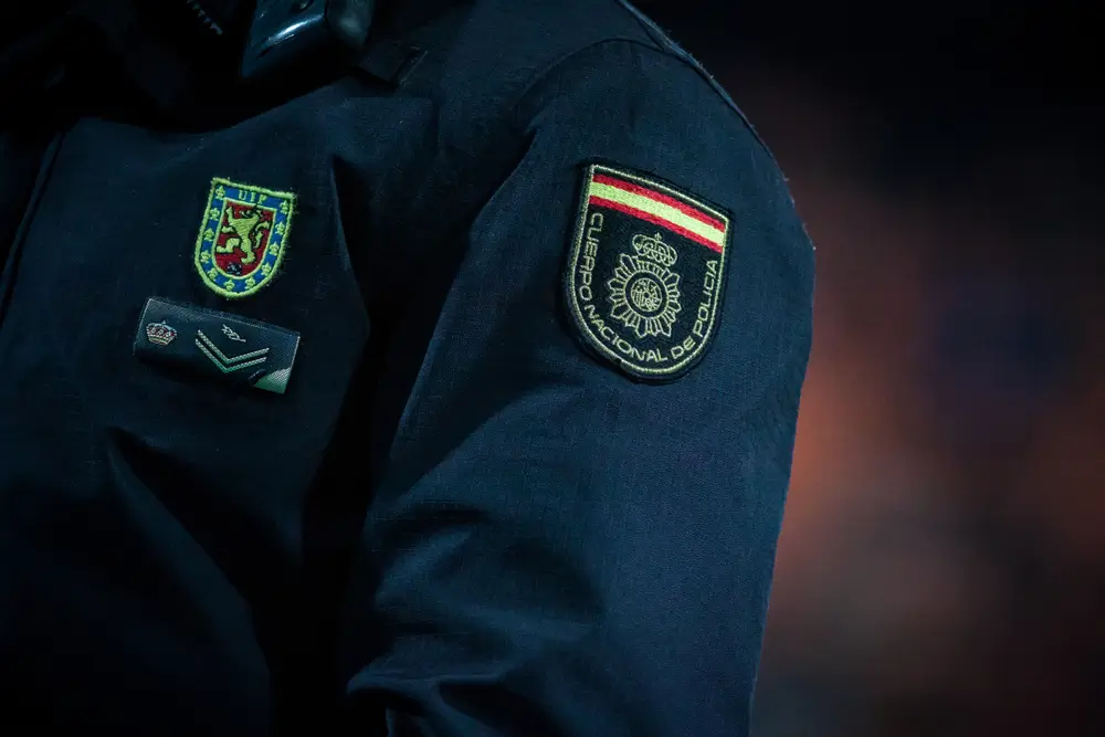 Detalle de las divisas, galones y el escudo oficial en el uniforme de un agente de la Policía Nacional.